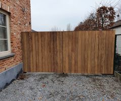 Eenvoudige houten poort met metalen accenten op de oprit